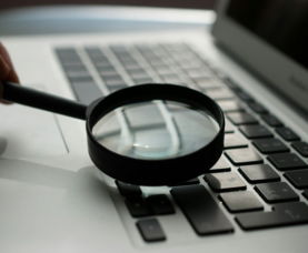 magnifying glass near gray laptop computer